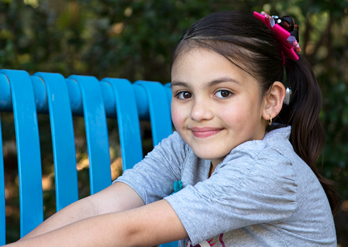 Junges Mädchen mit Cochlear Implantat lächelt in die Kamera
