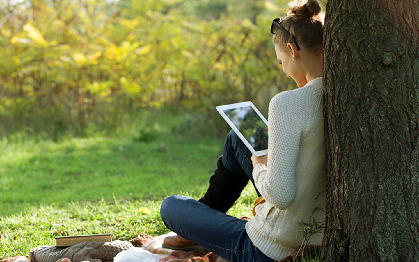 Seorang wanita sedang menggunakan iPad di taman