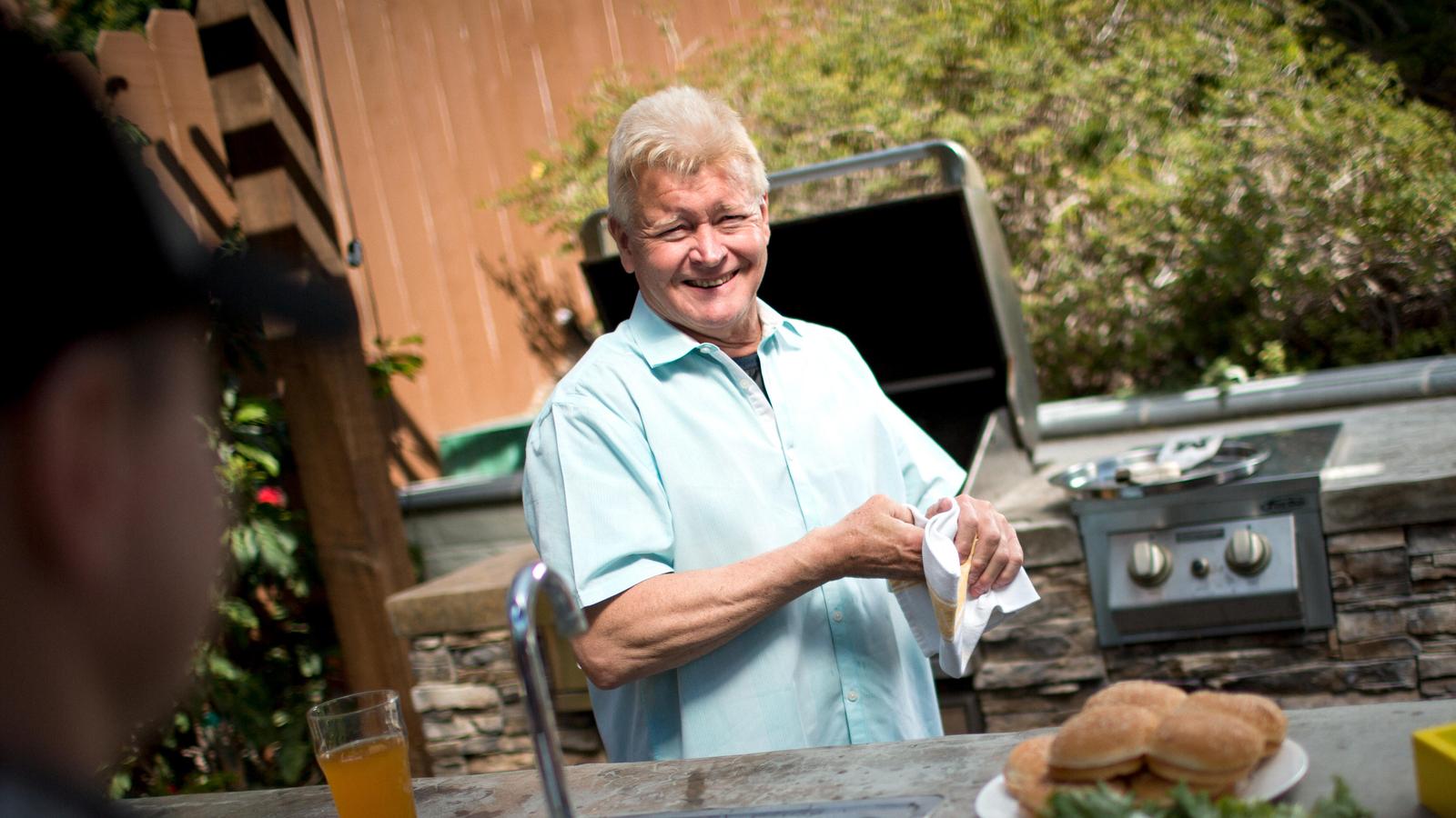 A man smiles at the camera at a BBQ